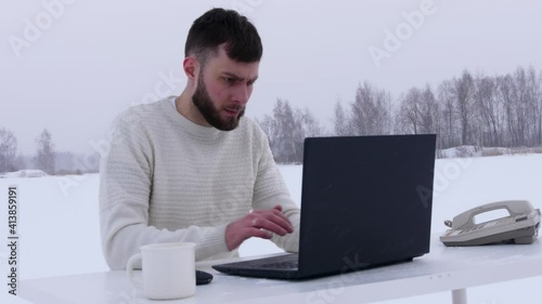 young office worker in the field. Office manager in the snow. A man with a laptop in a snowy field. work in lockdown