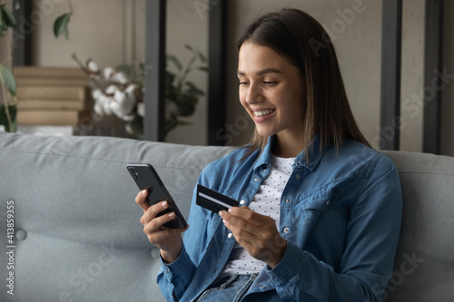 Spending money with pleasure. Happy young female client of reliable bank use card to buy order prepay goods online at web store via special app. Smiling millennial woman engaged in internet shopping