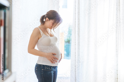 Happy pregnant mother in blue jeans is hugging her naked tummy, close up Free Download Happy pregnant mother in blue jeans is hugging her naked tummy, close up - GFXLoad