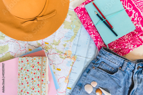 summer hat towel demin shorts notebooks and books laid on map photo