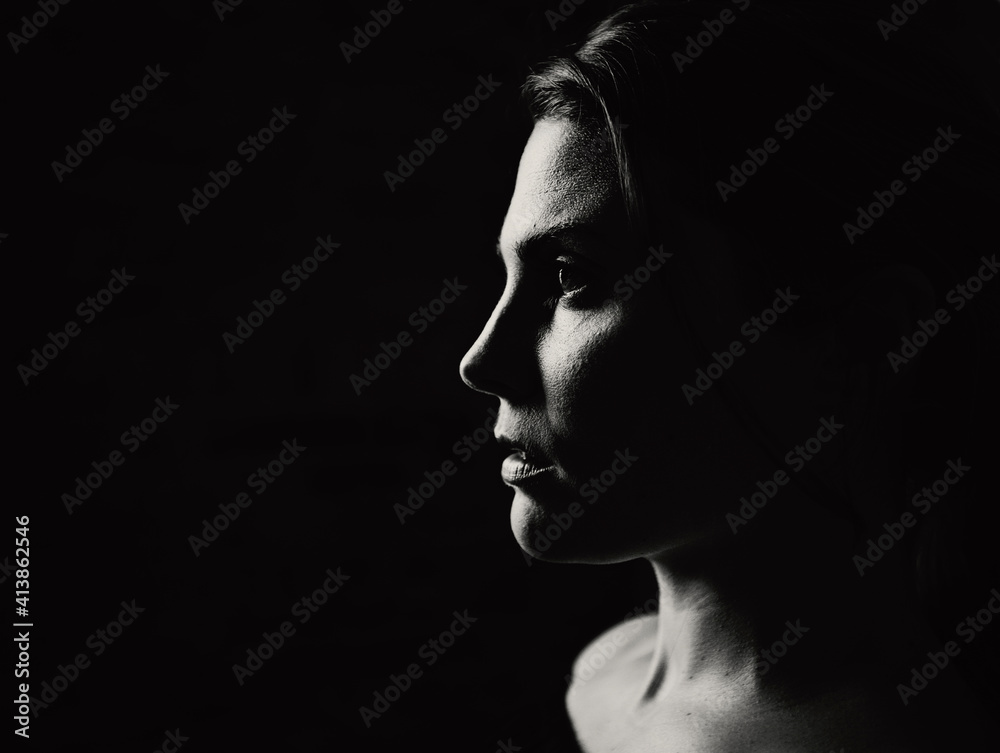 A closeup of a young woman in profile in dramatic light A closeup of a young woman in profile in dramatic light