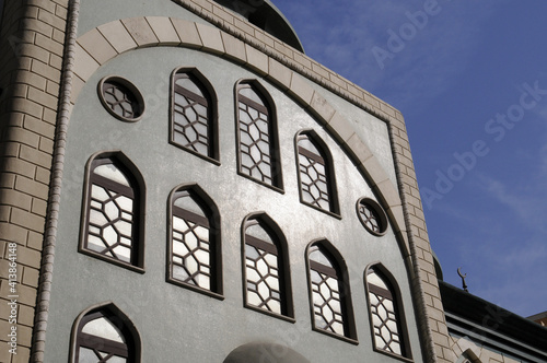 Façade de bâtiment en pierre, de style perse avec une arcade en briques, des fenêtres en vitraux en forme d'ogive et oeil de boeuf. Ancien Dubaï.