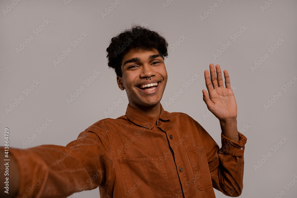 Photo of black man takes a selfie and smiles with perfect teeth. Male wears shirt, isolated grey color background Photo of black man takes a selfie and smiles with perfect teeth. Male wears shirt, isolated grey color background