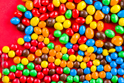 M&M's candy on the red background, colorful candy, multicolored gradient