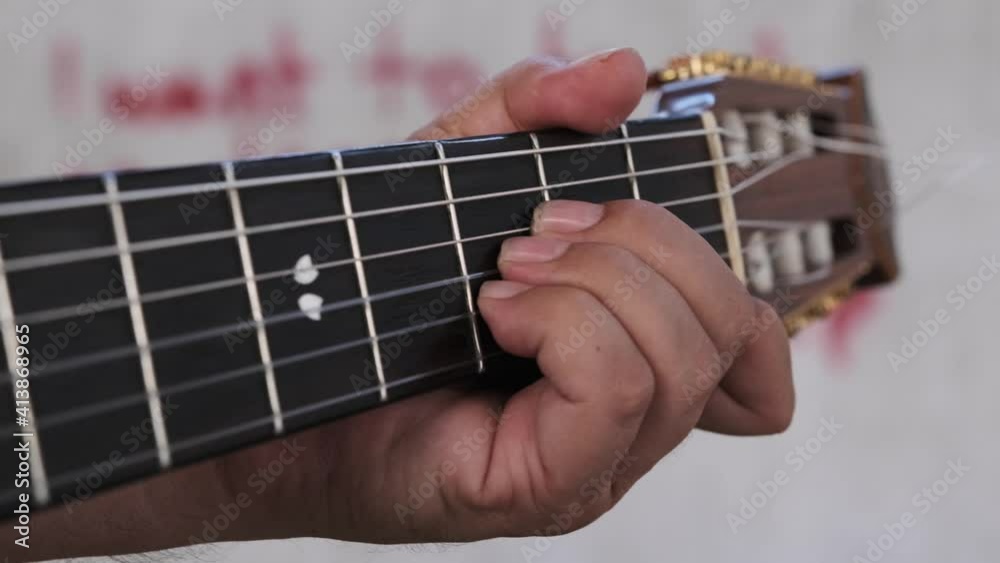 Close-up of playing guitar. A hand plays the fretboard on the neck of an acoustic guitar. Close-up of playing guitar. A hand plays the fretboard on the neck of an acoustic guitar.