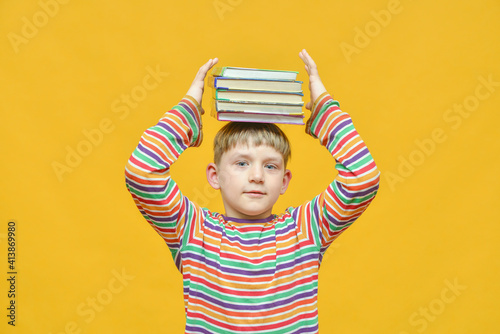 A joyful boy holds a bundle of textbooks on his head and wishes to gain knowledge.