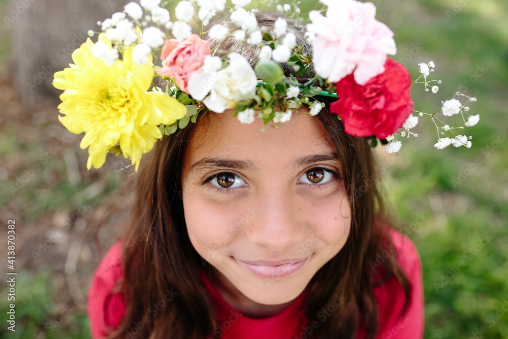 Tween girl smiles up at camera while wearing a flower head wreath Tween girl smiles up at camera while wearing a flower head wreath