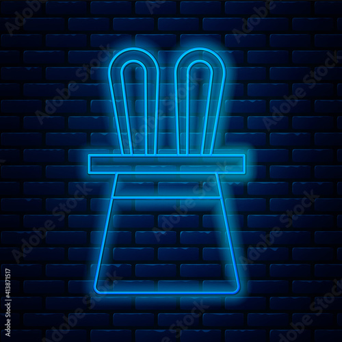 Glowing neon line Magician hat and rabbit ears icon isolated on brick wall background. Magic trick. Mystery entertainment concept. Vector.