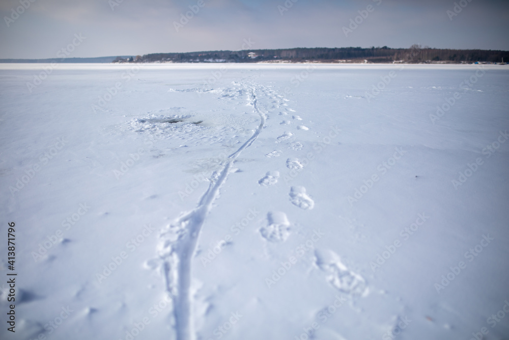 footprints on a frozen lake, snowy and cold winter, risky behavior