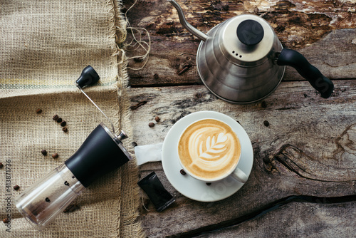 Manual grinder, kettle and creative coffee on the old table. photo