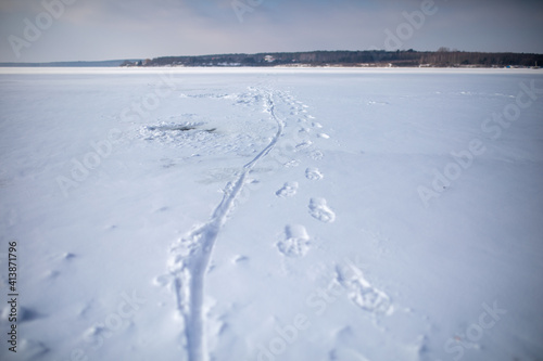 footprints on a frozen lake, snowy and cold winter, risky behavior