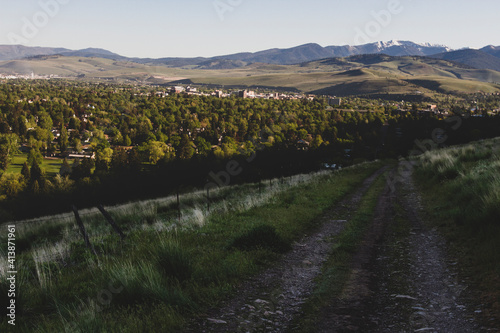 A dirt road leads to Missoula, Montana in spring with Snowbowl behind photo