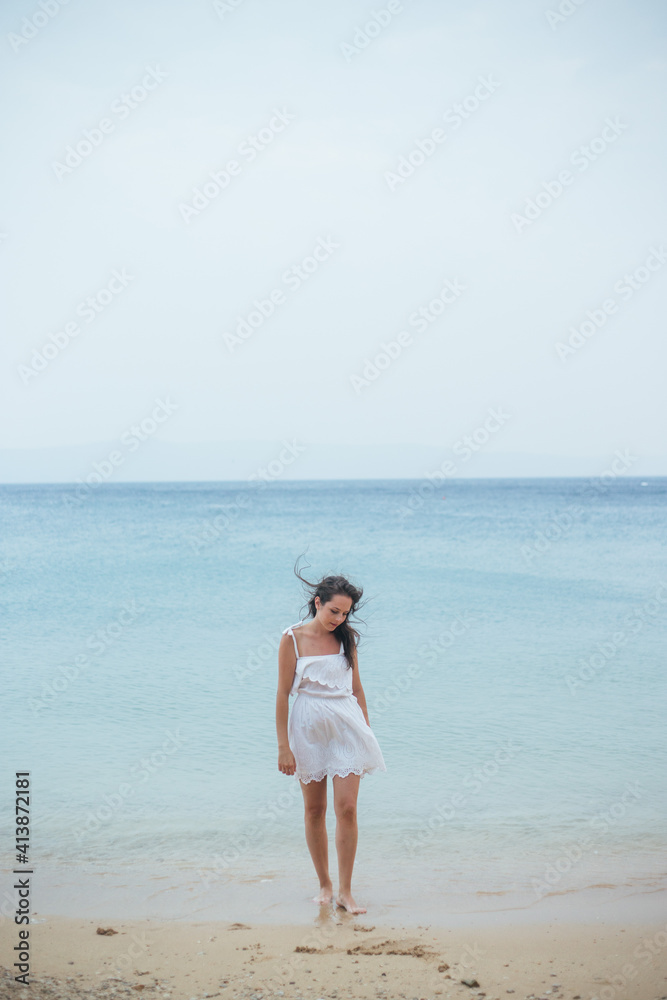 Young woman in summer dress walkin on beach sand Young woman in summer dress walkin on beach sand