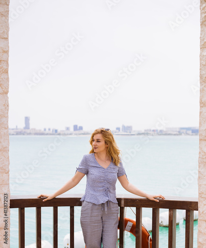 Young blond woman standing on terrace above the sea photo