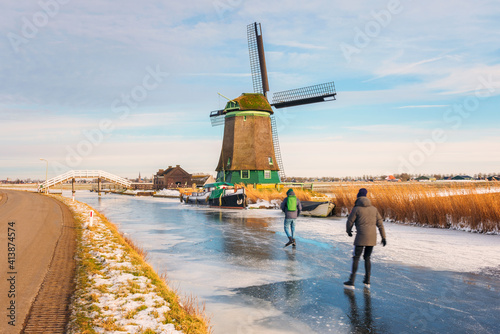 Two Ice Skaters skating on a frozen polder ditch in Opmeer, Netherlands on a cold February day in 2021