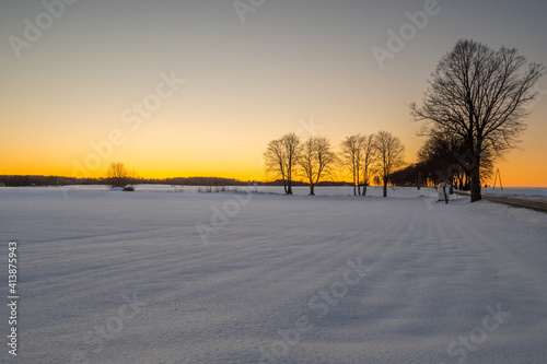 Winter rural landscape, snow covered field during sunset