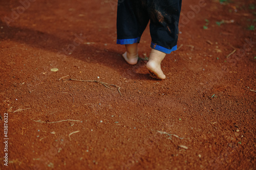 a boy playing on the dirty ground barefoot