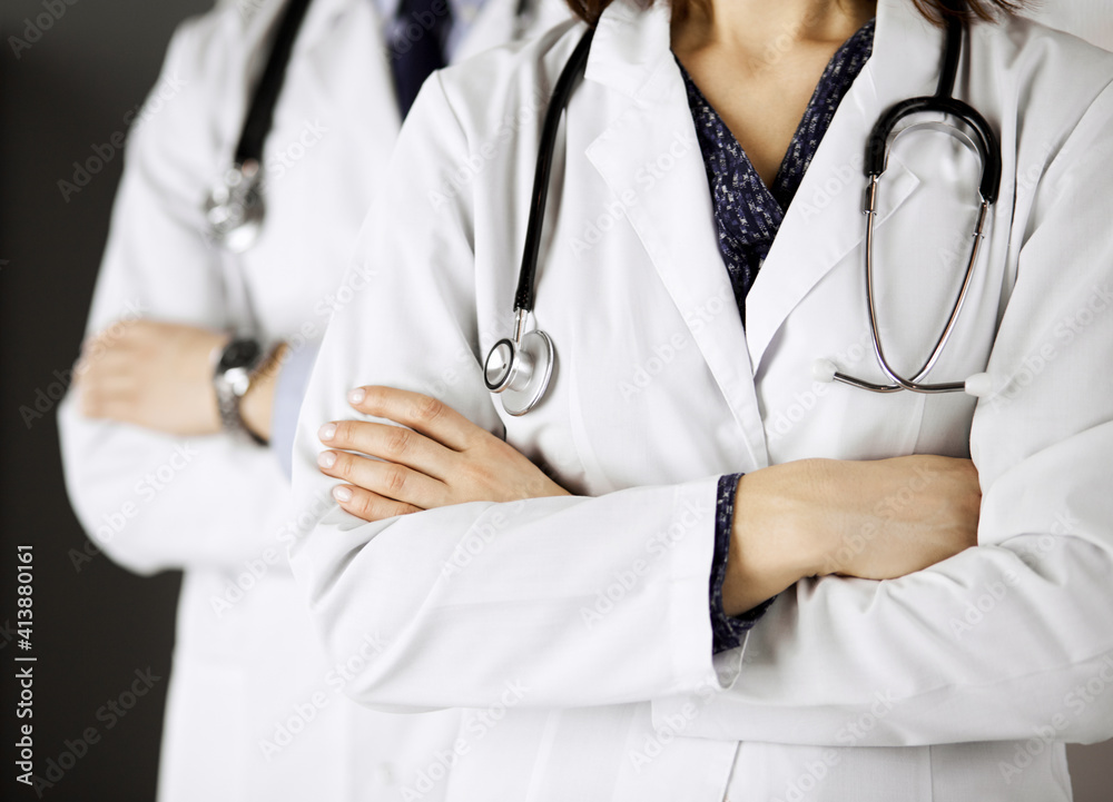 Group of modern doctors standing as a team with arms crossed in hospital office and ready to help patients. Medical help, insurance in health care, best disease treatment and medicine concept Group of modern doctors standing as a team with arms crossed in hospital office and ready to help patients. Medical help, insurance in health care, best disease treatment and medicine concept