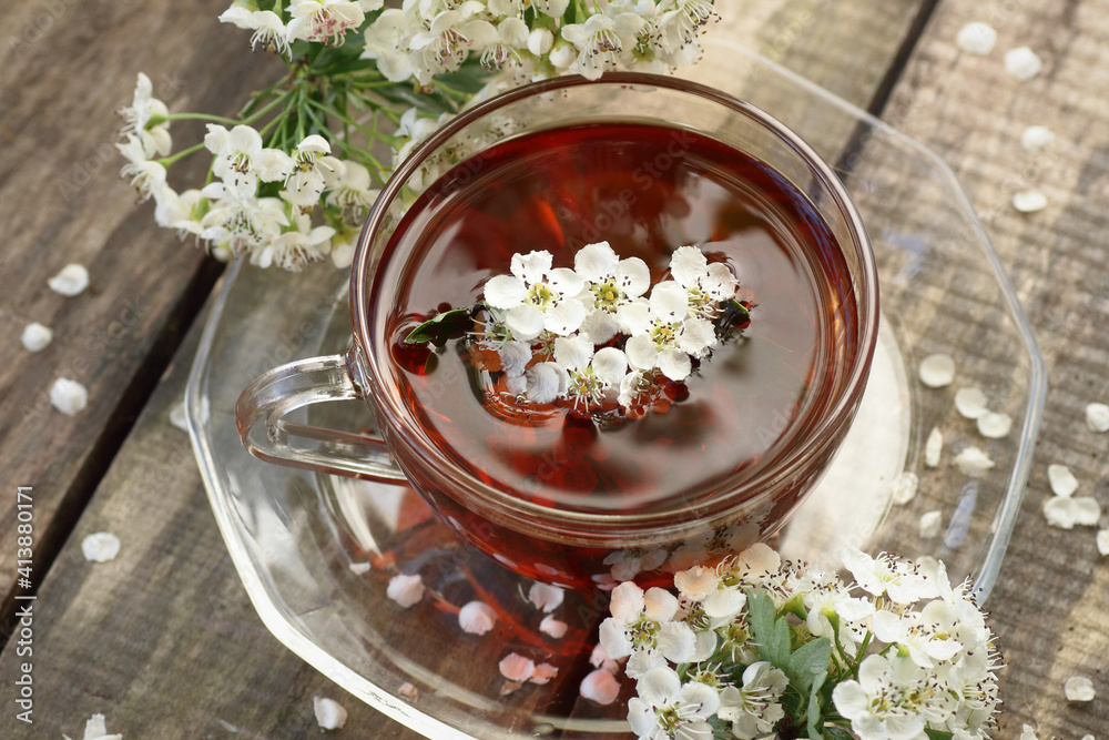 Hawthorn spring floral tea with spring blooming branches with flower buds on wooden background, closeup, copy space, vertical, herbal teas and natural medicine concept