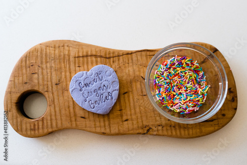 Flat lay of a purple decorated bookie with a bowl of sprinkles photo