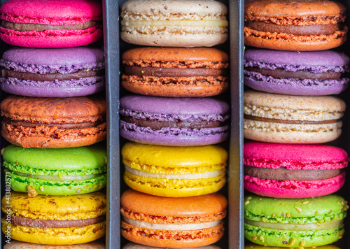 Various colorful macarons or French macaroons in a row in a gift box, sweet meringue-based confection made with egg white, icing sugar, granulated sugar, almond meal, and food colouring, close up