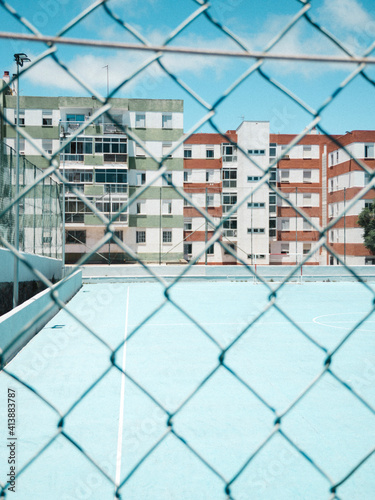 Blue football soccer court through fence with buildings in background photo