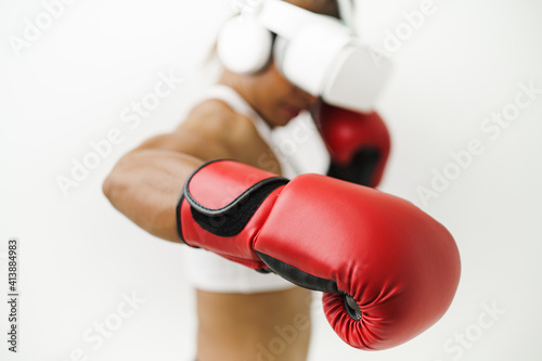 Medium close up shot of Asian woman wearing VR headset to exercise with simulation boxing games, Young female athlete boxer virtual reality combat experience activity. Boxing gloves selective focused.