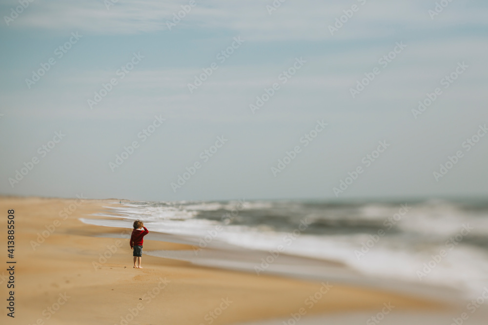 Side view of boy standing at shore against sky during sunny day Side view of boy standing at shore against sky during sunny day