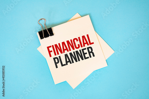 Text FINANCIAL PLANNER on sticky notes with copy space and paper clip isolated on red background.Finance and economics concept.