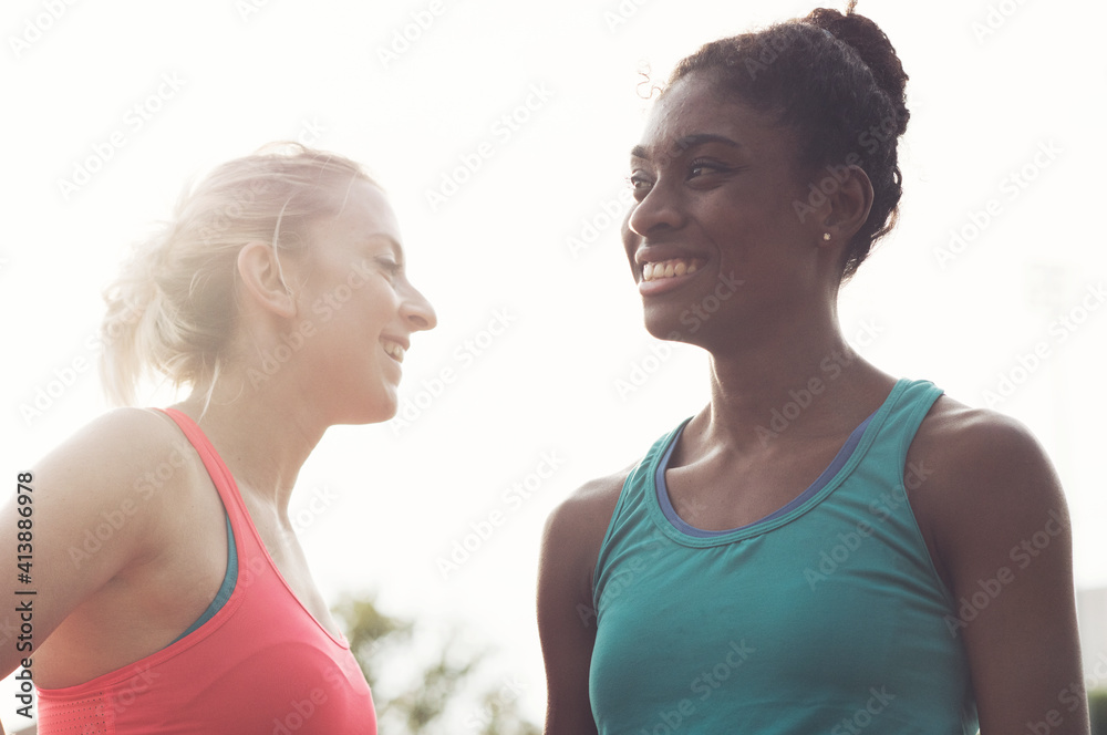 Low angle view of female athletes talking while standing against sky Low angle view of female athletes talking while standing against sky