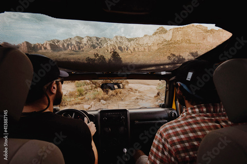 Rear view of friends traveling in off-road vehicle on dirt road