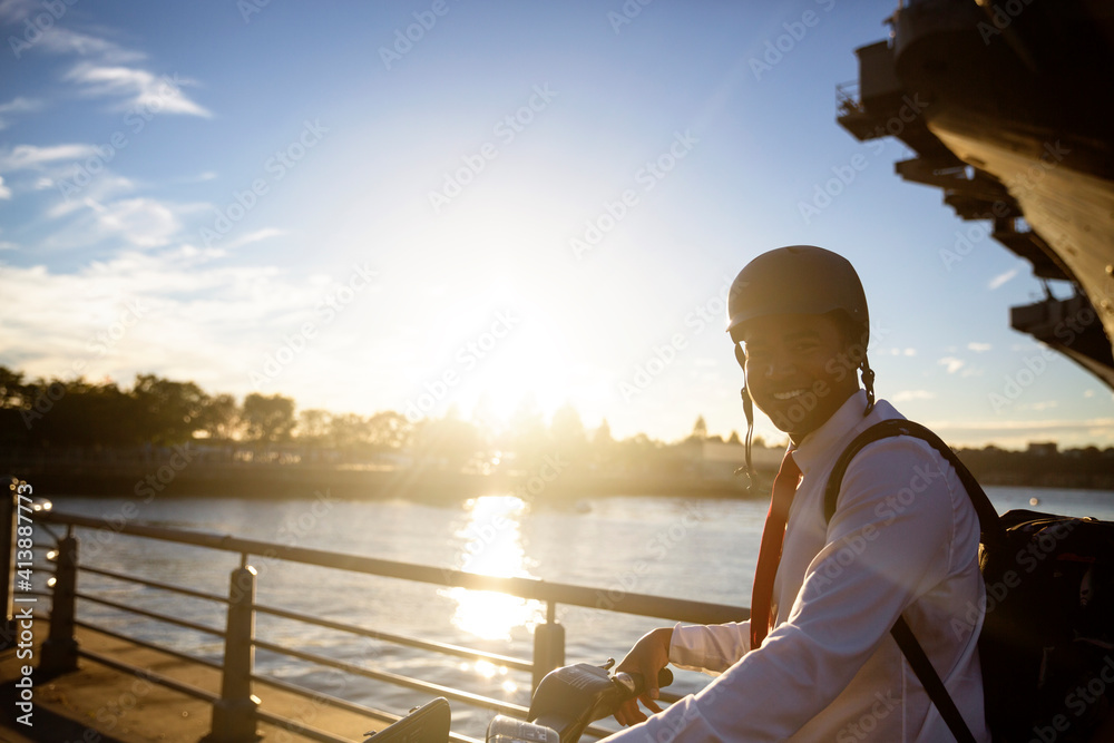 Portrait of businessman with bicycle standing against river during sunset Portrait of businessman with bicycle standing against river during sunset