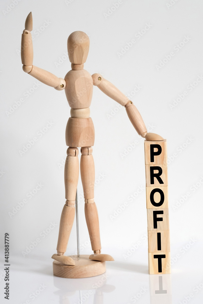 The wooden man raised his hand, and under his left hand he has cubes with the inscription - PROFIT The wooden man raised his hand, and under his left hand he has cubes with the inscription - PROFIT