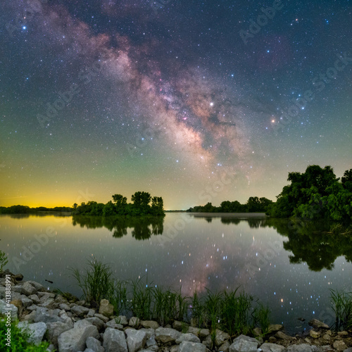 calm lake reflecting trees and stars at night photo