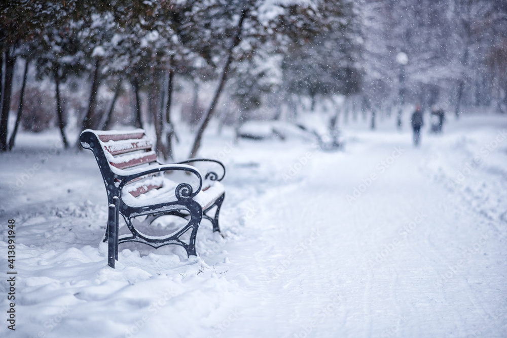 lonely park bench during snowfall on winter day