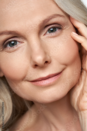 Foto Happy attractive 50 years old middle aged mature woman touching healthy soft face skin looking at camera
