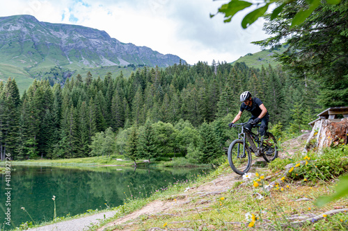 Riding his mountain bike near the lake and trees, les portes du soleil, Morzine, France
