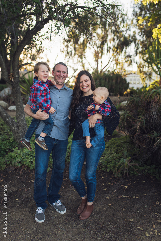 Portrait of happy parents carrying sons while standing at park Portrait of happy parents carrying sons while standing at park