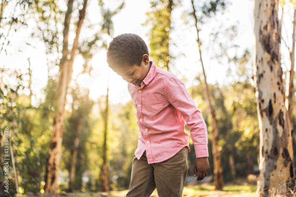 Low angle view of boy standing against trees in forest Low angle view of boy standing against trees in forest