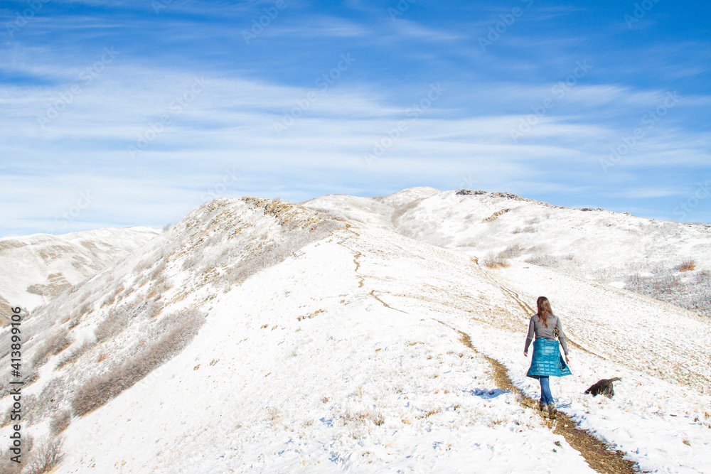 Rear view of woman walking on mountain against cloudy sky during winter Rear view of woman walking on mountain against cloudy sky during winter