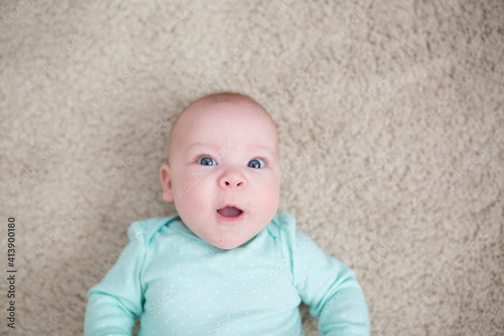 Overhead view of surprised baby girl with mouth open lying on rug at home Overhead view of surprised baby girl with mouth open lying on rug at home