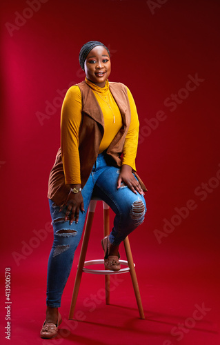 confident plus size african woman posing on chair in studio photo