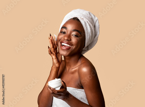 Beautiful young african american woman applying face cream