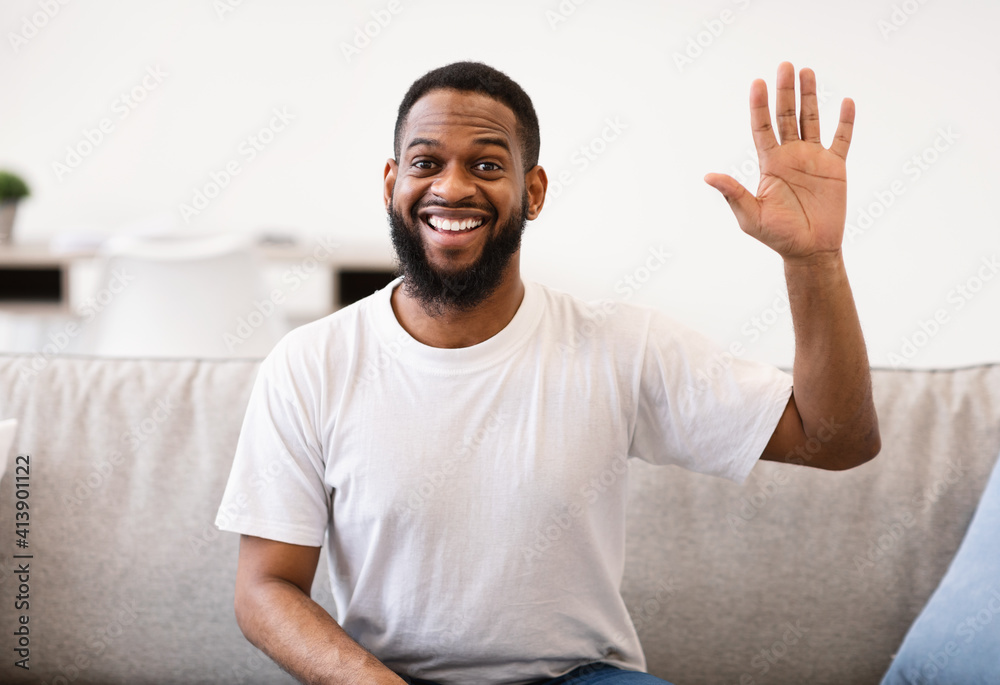 Cheerful African American Man Waving Hand Sitting On Couch Indoor Cheerful African American Man Waving Hand Sitting On Couch Indoor