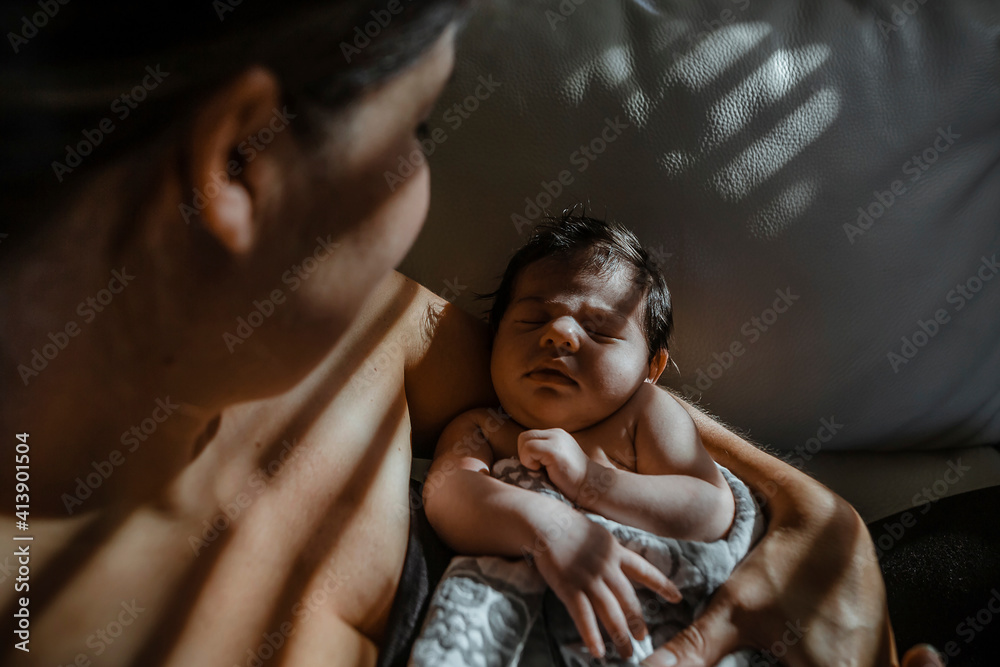 Overhead view of mother carrying sleeping newborn daughter at home Overhead view of mother carrying sleeping newborn daughter at home