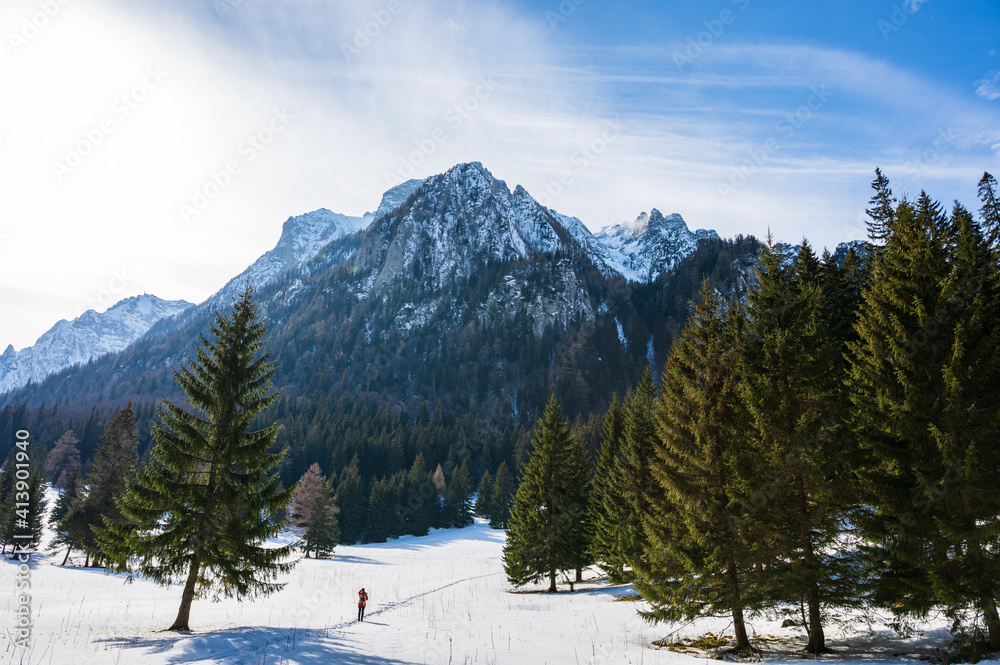 Hiker in front of high-rising mountain wall in Romanian Carpathian mountains in winter