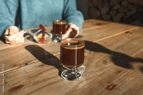 A cup of coffee in the foreground. The girl drinks coffee and eats sweets during a coffee break or relaxing in the background.