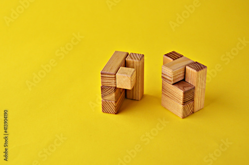 Two halves of a wooden cube logical game on a yellow background with a copy space. Solving logical problems. High quality photo