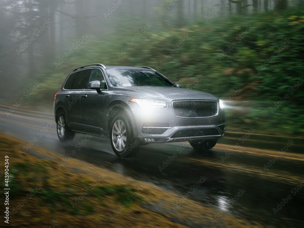 SUV automobile driving through foggy and rainy forest road