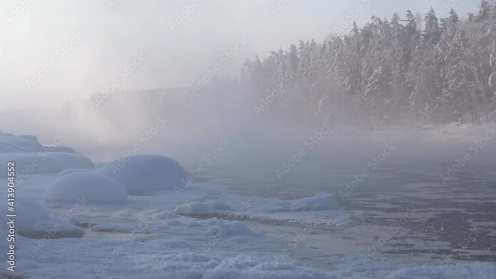 Misty river on frosty morning. Winter ice drift. Ice floats with current. On bank of river there are snowdrifts and frost, snowy forest looks through haze. Misty river on frosty morning. Winter ice drift. Ice floats with current. On bank of river there are snowdrifts and frost, snowy forest looks through haze.